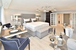 Essplatz, feststehendes Doppelbett mit Blick in den Eingangsbereich mit Küchenzeile