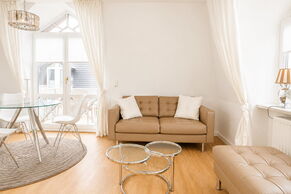 Helles Wohnzimmer mit Sofa, Essbereich und Zugang zum Balkon