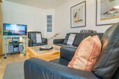 Wohnzimmer mit TV, gemütlicher Couchgarnitur und Sessel