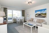 Wohnzimmer mit Sofagarnitur und Essplatz am Fenster