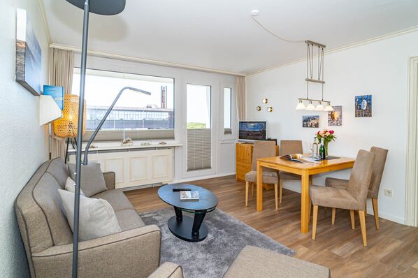 Ferienwohnung W 210 Wohnzimmer mit Sofa, Essplatz und Austritt auf die Loggia 