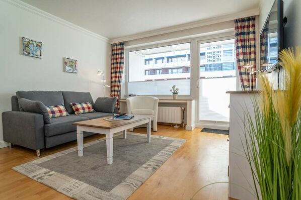 Wohnzimmer mit Schlafcouch und Zutritt zum Westbalkon