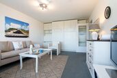 Wohnzimmer mit Sofagarnitur, TV und Schrankbetten