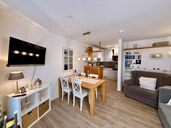 Wohnzimmer mit Sofa, Sessel, TV und Austritt auf die Südterrasse