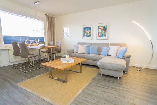 Wohnzimmer mit Sofagarnitur und Essplatz am Fenster