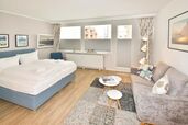 Wohn-/Schlafbereich mit Sofa, feststehendem Doppelbett und Zugang zur Ostloggia