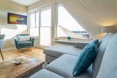 Wohnzimmer mit Sofaecke, Sessel, TV und Austritt auf den Balkon