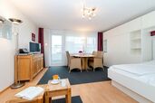 Wohn-/Schlafzimmer mit Doppelbett und Essplatz am Fenster