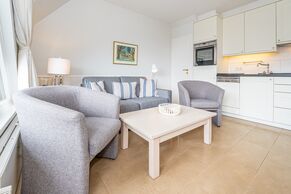Wohnzimmer mit Sofa, Sessel und offener Küchenzeile