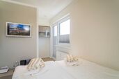 Wohn-/Schlafbereich mit feststehendem Doppelbett und Zutritt zum Westbalkon