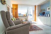 kombinierter Wohn-/Schlafraum mit Sofa, Sessel, TV und Austritt auf die Loggia