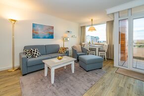 Wohnzimmer mit Sofa, Schrankbett und TV 